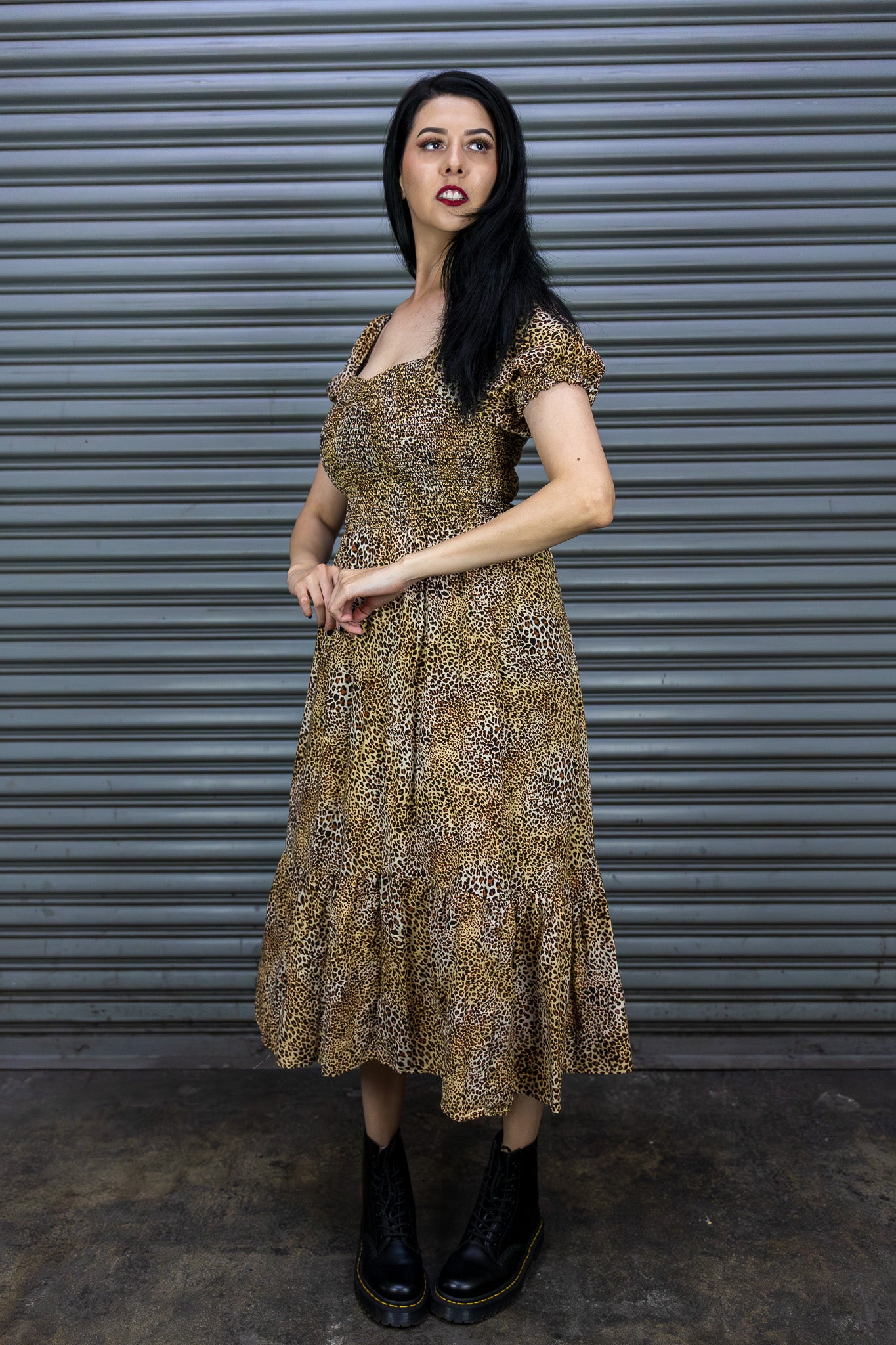 Woman wearing a patterned dress standing in front of a metal shutter.