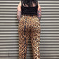 Person wearing leopard print pants standing in front of a metal shutter.