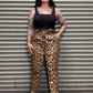 Person wearing leopard print pants and a black top standing in front of a metal shutter.