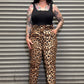 Person wearing leopard print pants and a black top standing in front of a metal shutter.