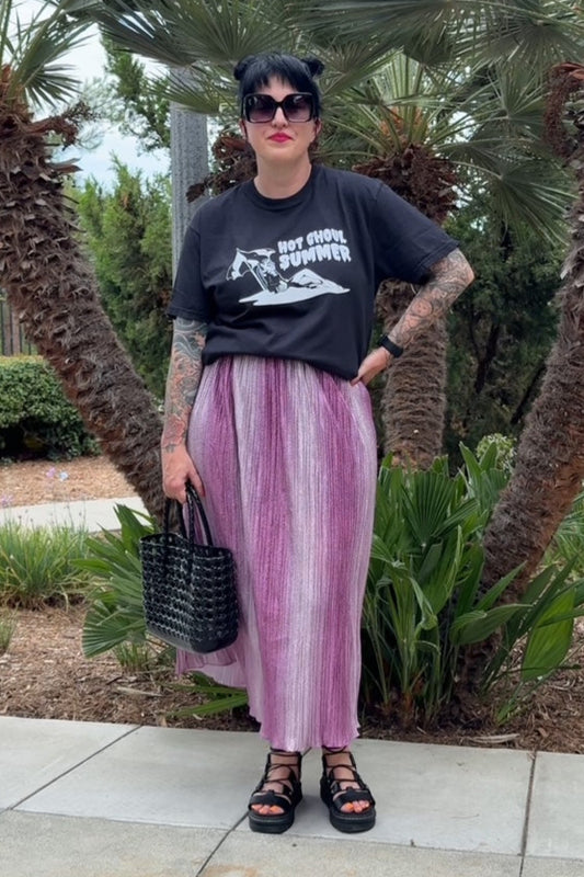Person wearing a black t-shirt and pink pants standing in front of palm trees.