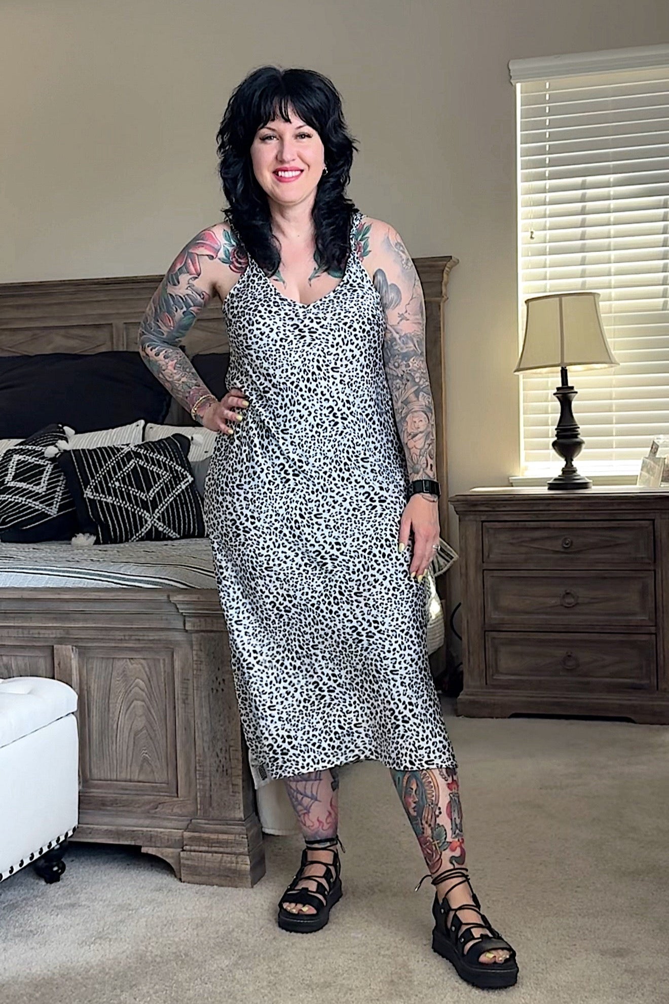 Woman in a patterned dress standing in a bedroom