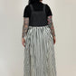 Person wearing a black top and striped skirt against a white background