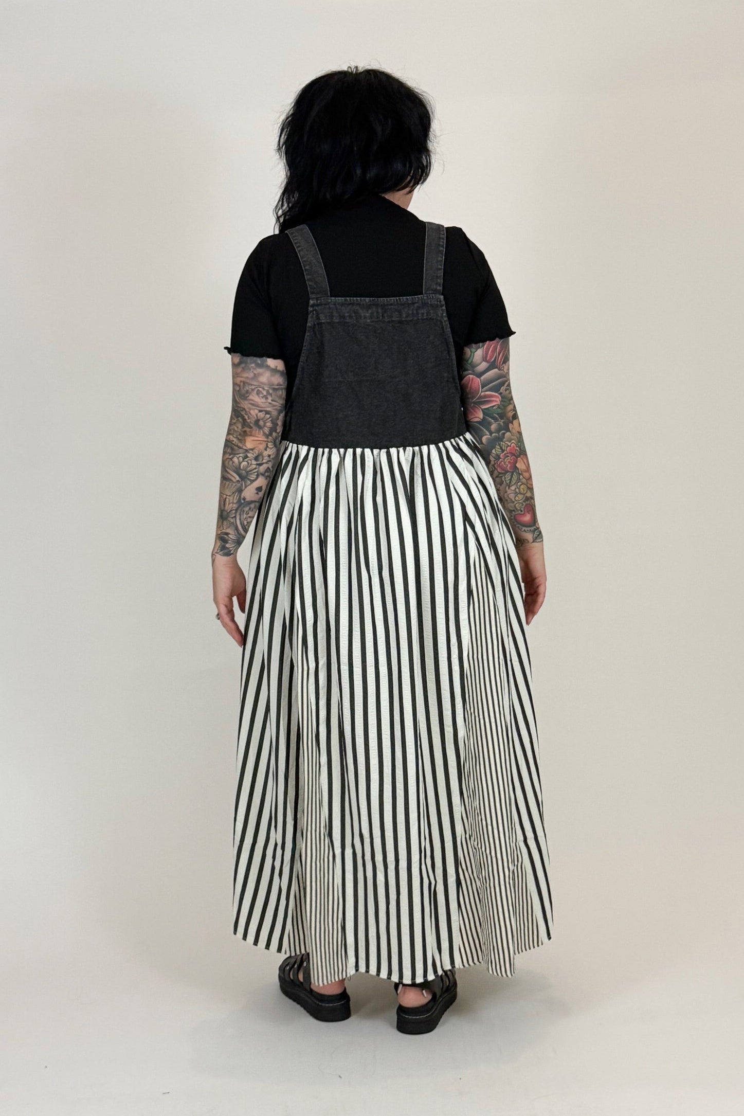 Person wearing a black top and striped skirt against a white background