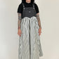 Person wearing a black t-shirt and striped overalls on a white background