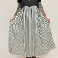 Person wearing a black and white striped apron over a black t-shirt on a plain background