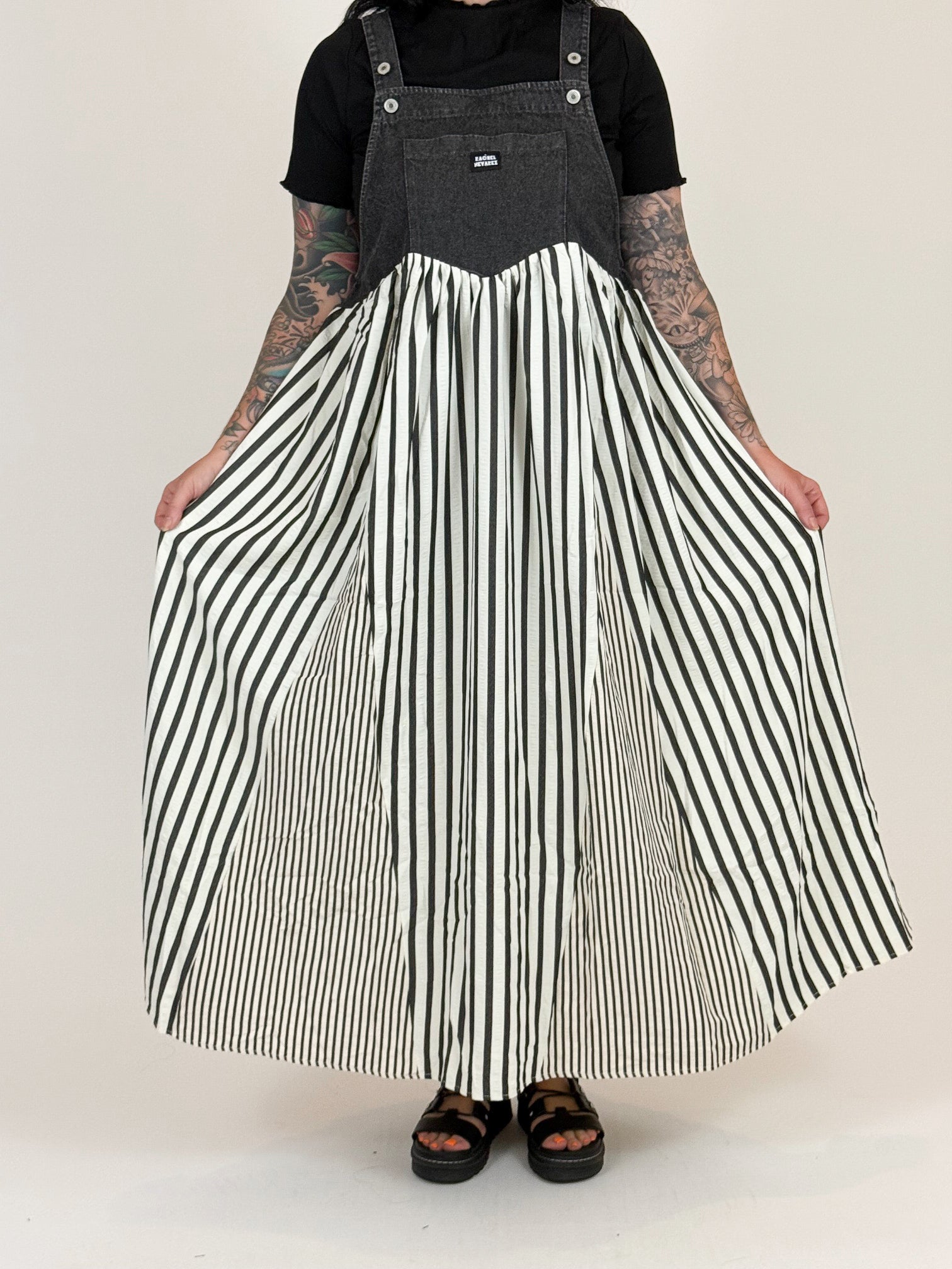 Person wearing a black and white striped apron over a black t-shirt on a plain background