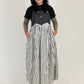 Person wearing a black and gray top with a long black and white striped skirt on a white background