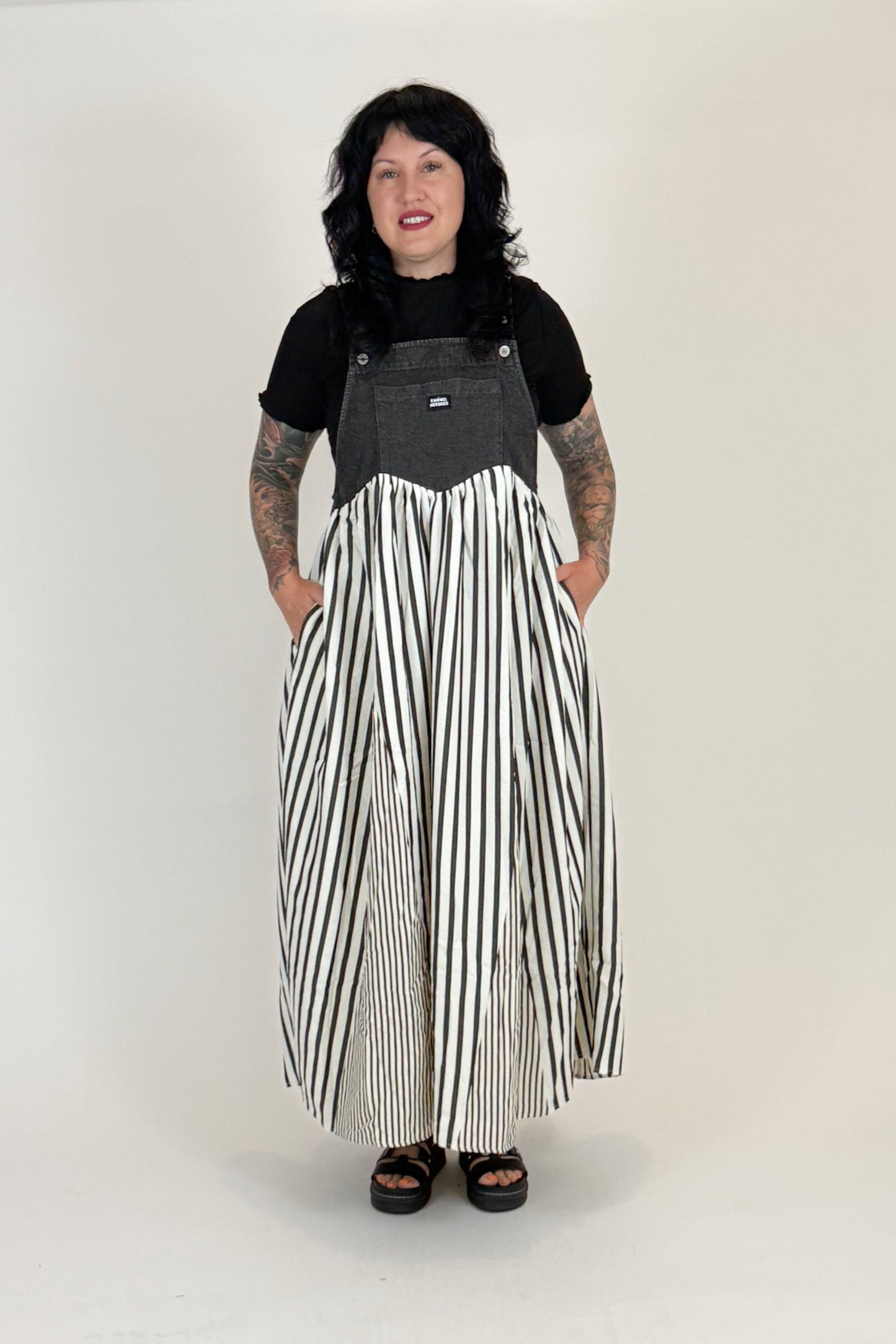 Person wearing a black and gray top with a long black and white striped skirt on a white background