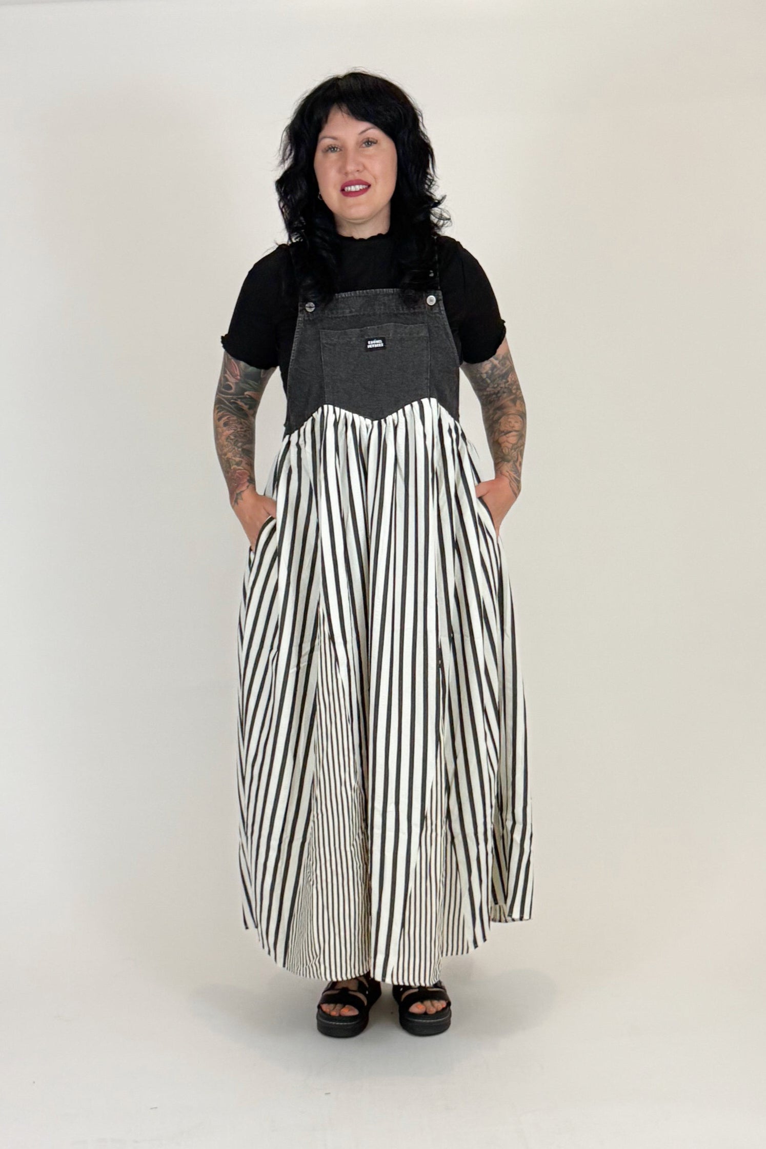 Person wearing a black and gray top with a long black and white striped skirt on a white background