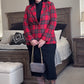 Person wearing a red plaid blazer in a bedroom setting