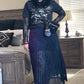 Person wearing a black outfit with a hat, top, skirt, and boots in a room.