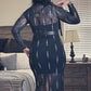 Person wearing a black lace dress with cut-out details in a bedroom setting.