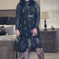 Person wearing a black outfit with sheer panels in a room.