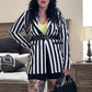 Woman in a black and white striped outfit standing in a bedroom.