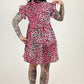 Person wearing a patterned dress standing against a white backdrop