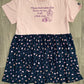 An upcycled tee dress with a navy candy print skirt and a pink solid color top with text on it.