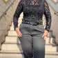Person wearing a patterned shirt and gray jeans standing on steps with a blue sky background