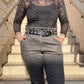 A person wearing a long sleeve black mesh top with a bow pattern, paired with gray trousers, standing on steps.