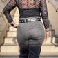 Person wearing a sheer black top and gray pants on stone steps.