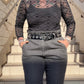 Person wearing a black patterned top and gray pants on stone steps.