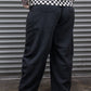 Person wearing a checkered shirt and black pants standing in front of a metallic shutter.