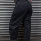Person wearing black pants and a checkered shirt standing in front of a gray metal shutter.