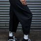 Person wearing black pants and black and white sneakers in front of a metal shutter.