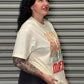 Person wearing a vintage-style t-shirt with graphic design against a metallic shutter background