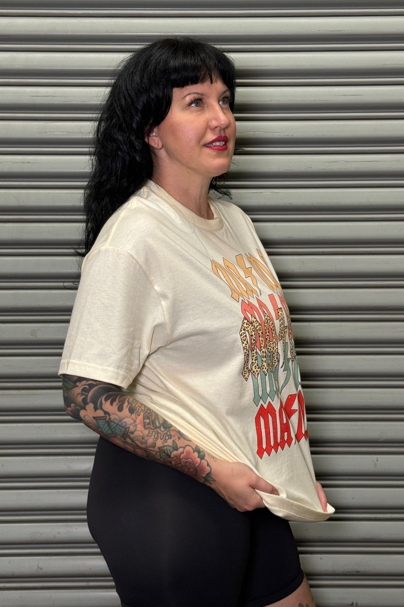 Person wearing a vintage-style t-shirt with graphic design against a metallic shutter background