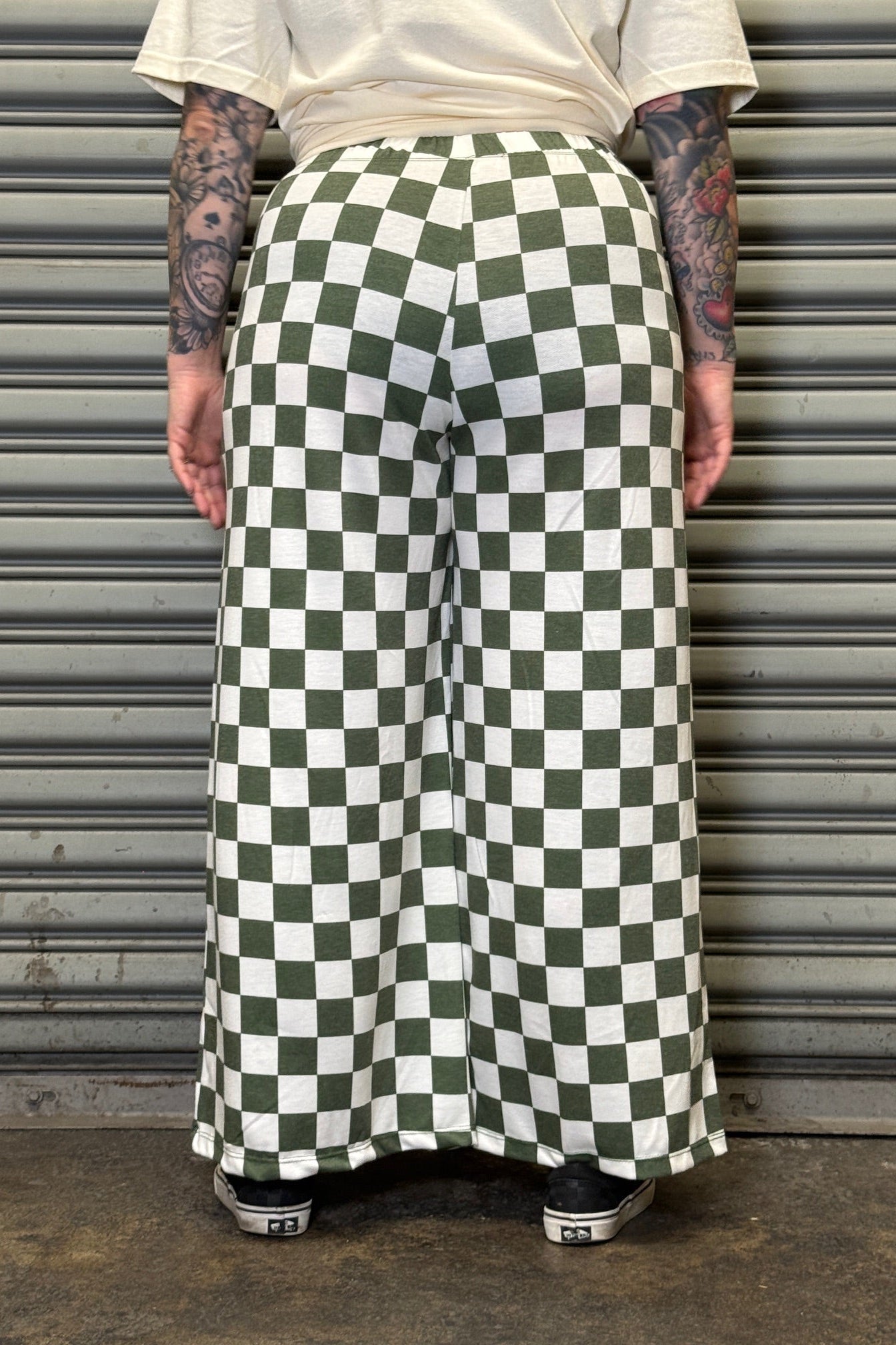 Person wearing a green and white checkered skirt against a metallic shutter background