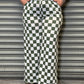 Person wearing a graphic t-shirt and green and white checkered pants against a metallic shutter.