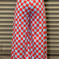 Person wearing red and white checkered pants standing against a metallic shutter.