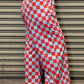 Person wearing red and white checkered pants standing against a metallic shutter.