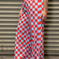 Person wearing red and white checkered pants standing against a metal shutter.