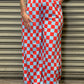 Person wearing red and blue checkered pants standing against a metallic shutter.
