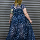 Person wearing a blue leopard print maxi dress standing in front of a metal shutter.
