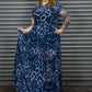 Person wearing a blue leopard print maxi dress standing against a metallic shutter.