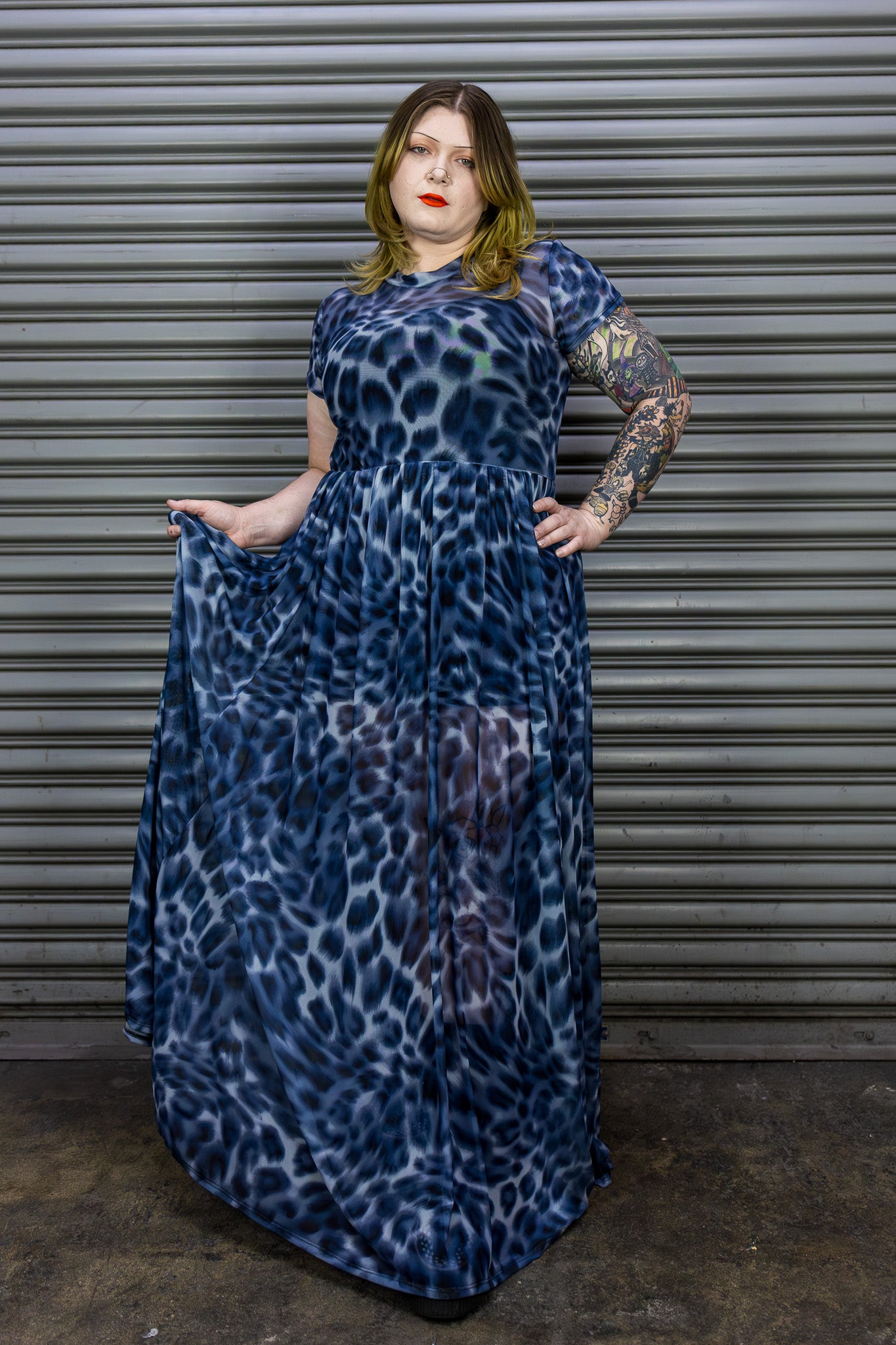 Person wearing a blue leopard print maxi dress standing against a metallic shutter.