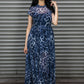 Woman wearing a blue patterned maxi dress standing in front of a metal shutter.