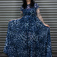 Woman wearing a blue leopard print dress standing against a metal shutter.