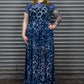 Woman wearing a blue leopard print maxi dress standing in front of a metal shutter.