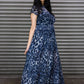 Woman wearing a blue leopard print dress standing in front of a metal shutter.
