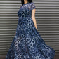 Woman wearing a blue leopard print dress in front of a corrugated metal wall.
