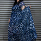 Woman holding a blue leopard print dress against a metal shutter background.
