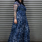 Person wearing a blue leopard print dress standing in front of a metal shutter.