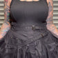 Person wearing a black sleeveless top and skirt with tattoos on arms and neck.