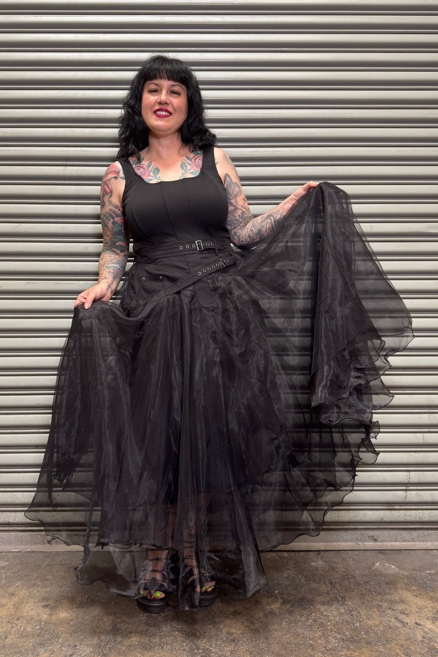 Woman holding a black sheer overlay against a metal shutter background
