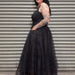 Woman wearing a black dress standing in front of a metal shutter.