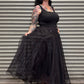 Woman wearing a black dress with sheer sleeves against a metal shutter background